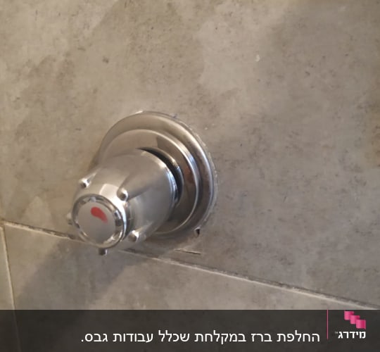 ברז מים מתכת על קיר אריחים